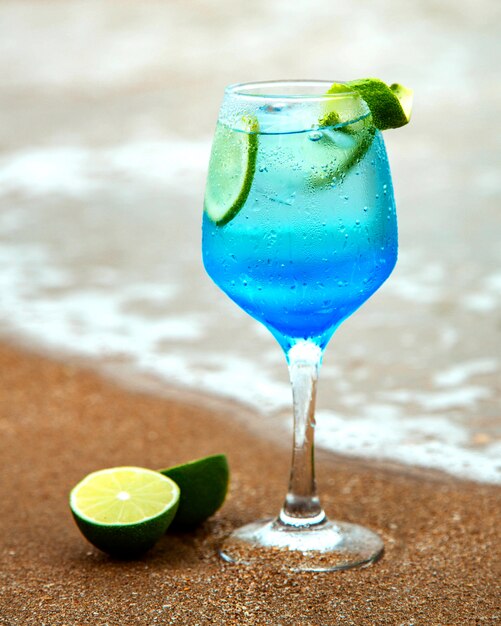 Blue drink with lime on sea shore