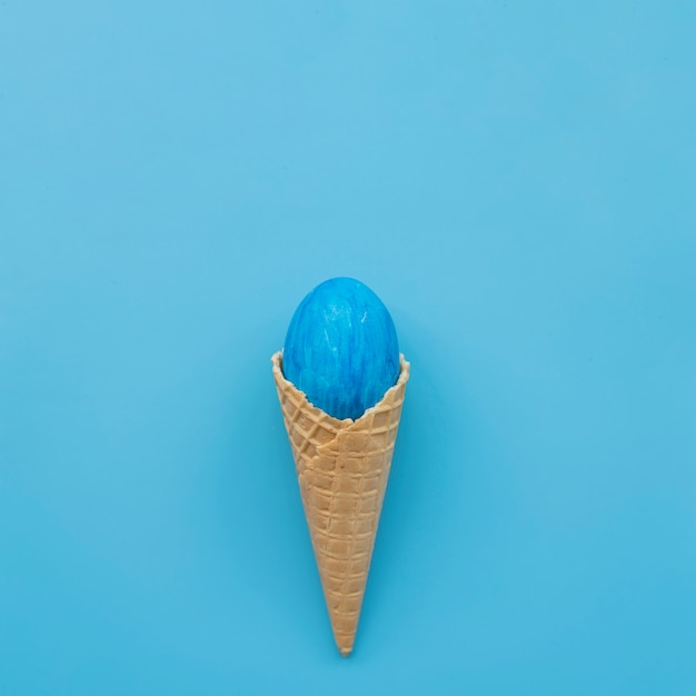 Blue egg in waffle cone on blue background