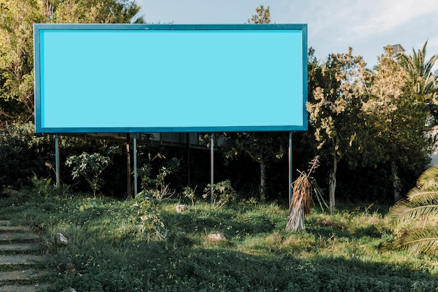 Free photo blue empty billboard on green meadow