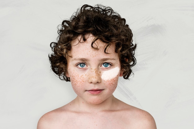 Blue eyed boy with freckles and white paint on his cheek