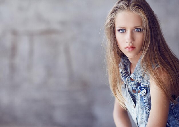 Blue eyes woman with long blond hair in denim jacket.