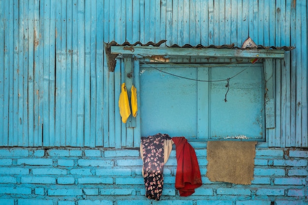 Blue facade of an old wooden suburban building with clothes hanged on the window