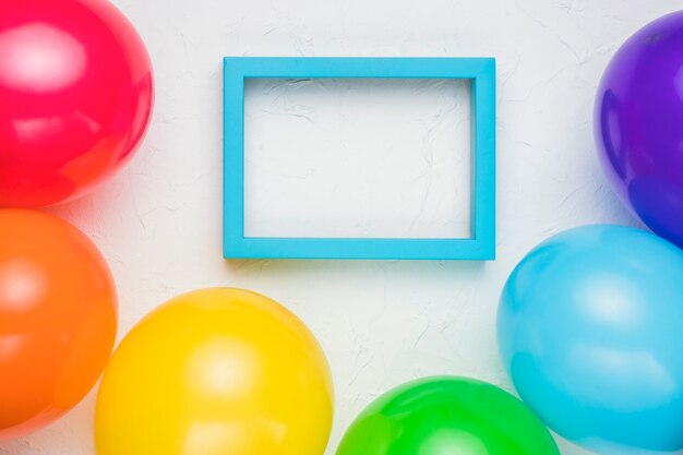 Blue frame and colorful balloons on white surface