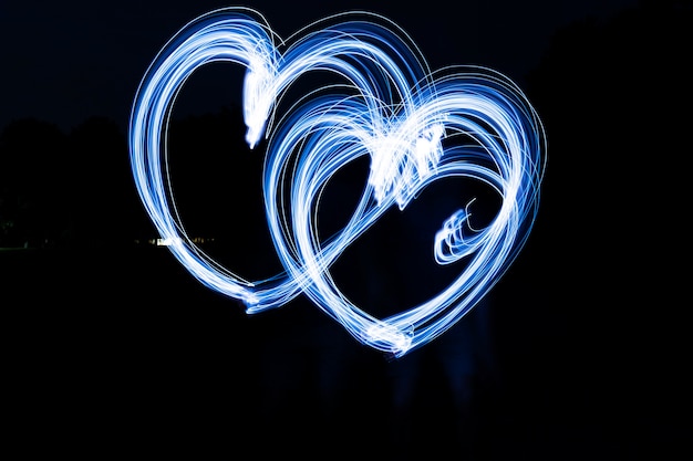 Free photo blue heart shaped light painting with dark background