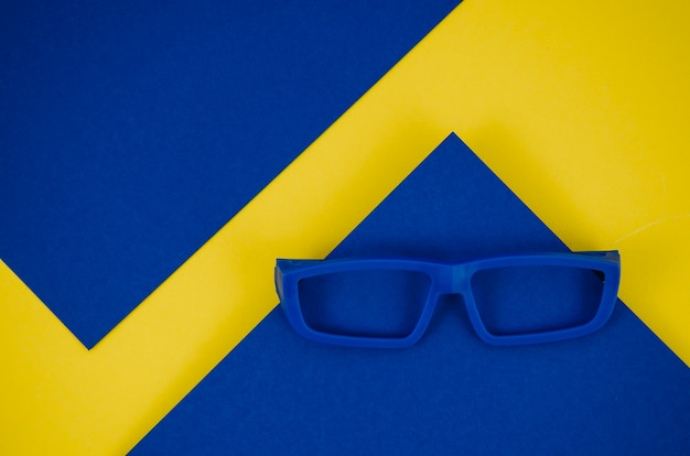 Free photo blue kids eyeglasses on blue and yellow background