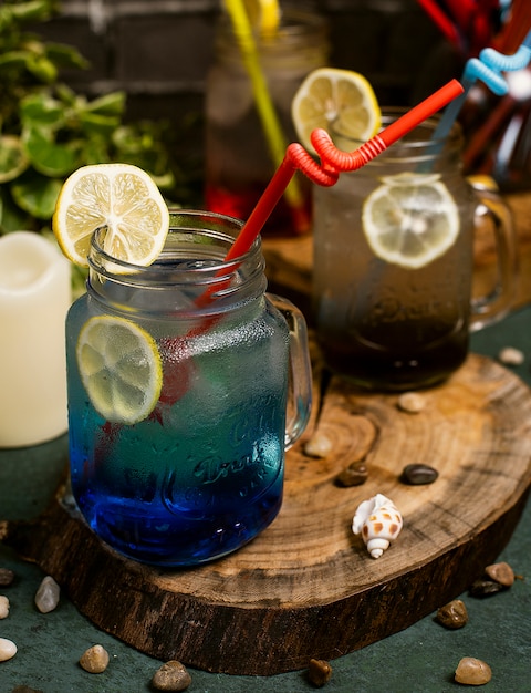 Blue lagoon cocktail with lemon slices inside jar with stick   