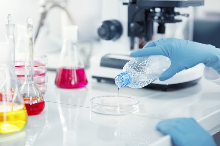 Free Photo blue latex gloves holding plastic bottle and pouring transparent liquid