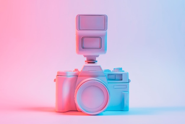 Free photo blue light on vintage painted pink camera against pink backdrop