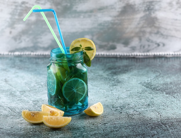 A blue mojito jar with lemon and mint on shiny background.