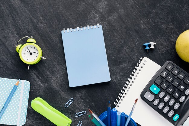 Blue notebook near office implements on blackboard