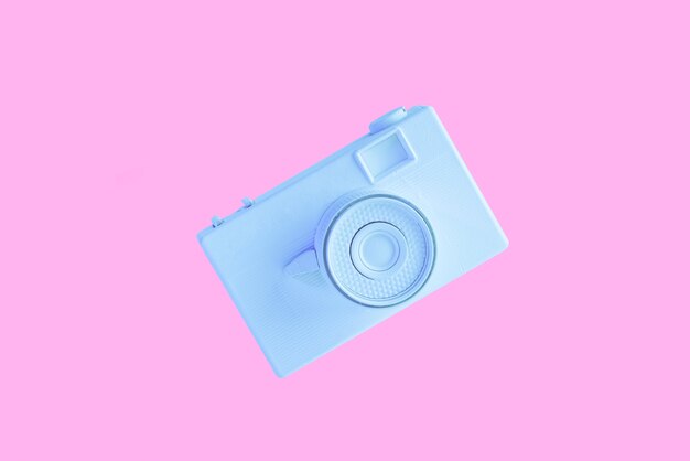 Blue painted camera in air against pink background