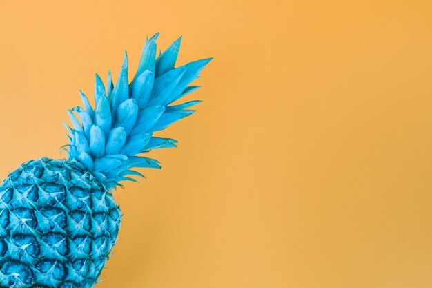 Blue painted pineapple against yellow backdrop