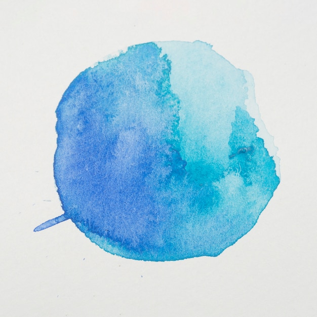 Синие краски в виде круга на белой бумаге