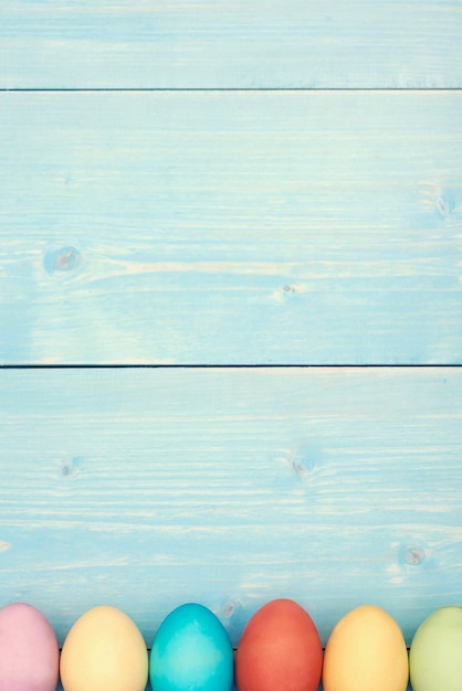 Free photo blue pastel plank and colorful easter eggs