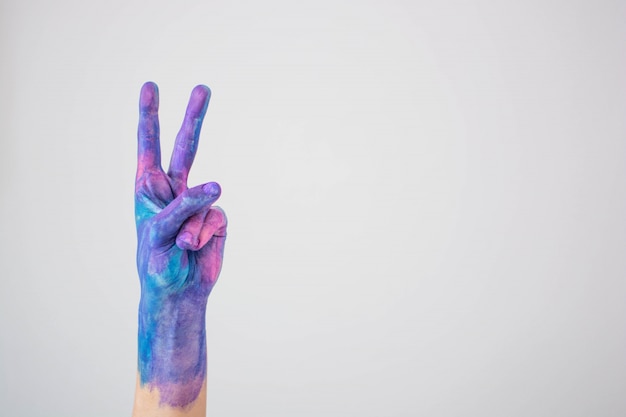 Blue and pink colored painted hand gesturing peace sign