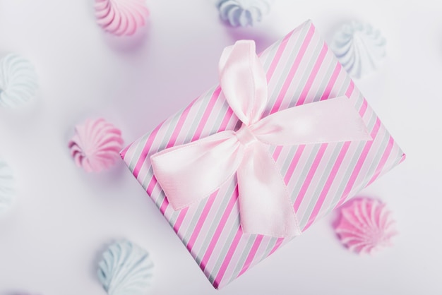 Blue and pink whipped cream around the present box tied with satin ribbon