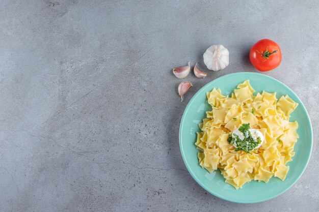 石の背景に茹でたおいしいパスタの青いプレート。