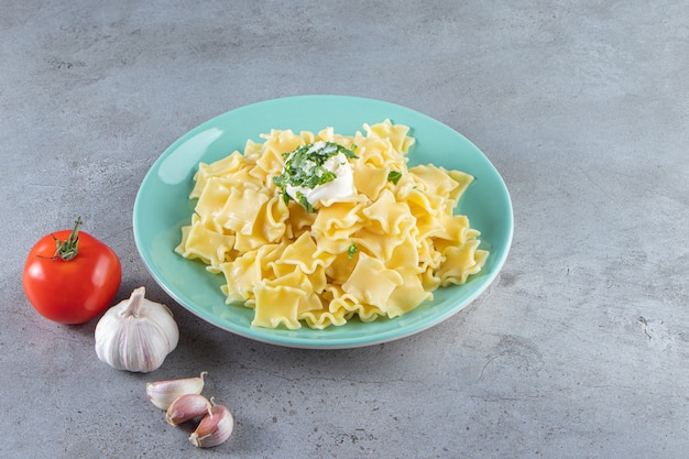 Blue plate of boiled delicious pasta on stone background. 