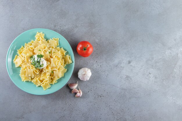 Blue plate of boiled delicious pasta on stone background. 