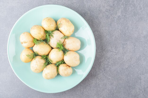 A blue plate of boiled potatoes with fresh dill 