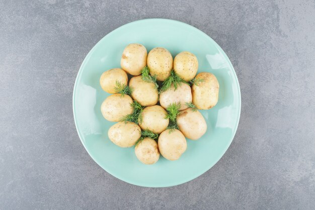 A blue plate of boiled potatoes with fresh dill 