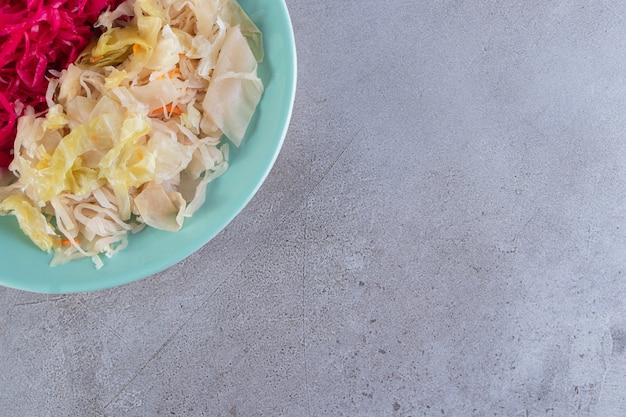 Free photo blue plate of cabbage sauerkraut varieties on stone table.