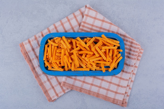 Blue plate of crunchy potato chips on stone table. 