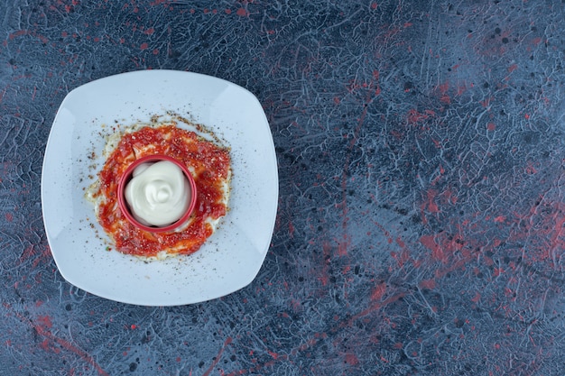 A blue plate of fried egg with spices and tomato sauce. 