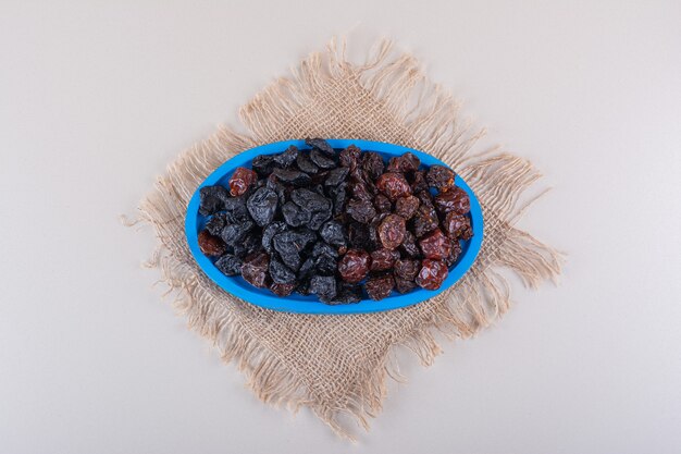 Blue plate full of dried tasty plums on white background. High quality photo