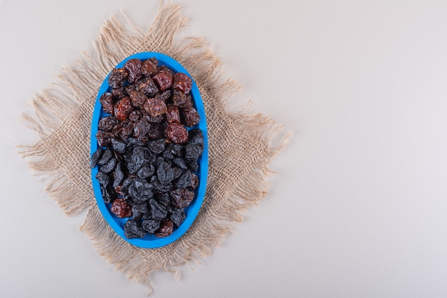 Blue plate full of dried tasty plums on white background. High quality photo