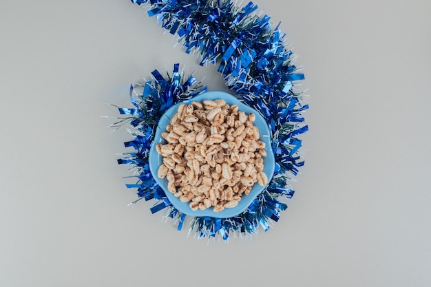 Free photo a blue plate full of healthy cereals with a christmas garland .