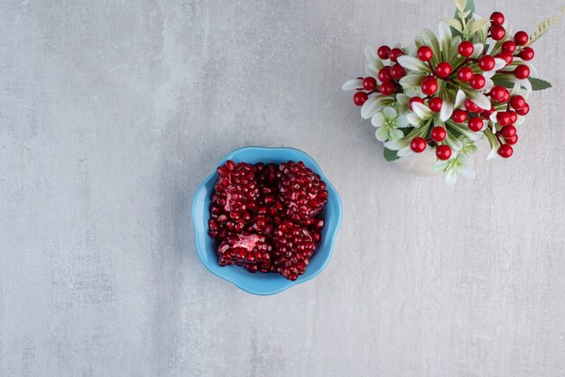 A blue plate full of pomegranate on gray table.