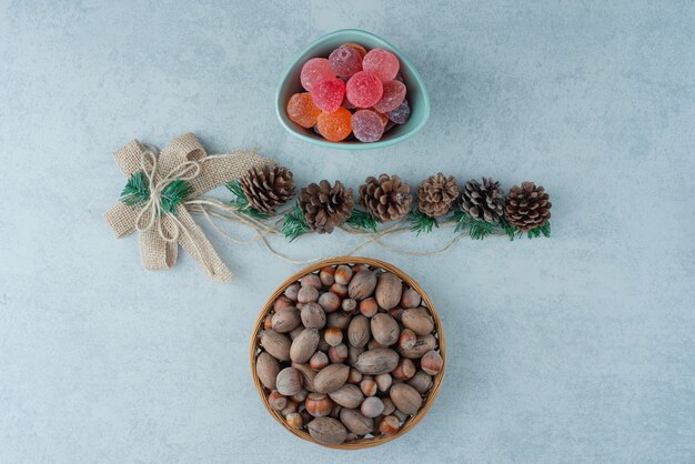 Голубая тарелка мармелада с маленькими рождественскими шишками на мраморном фоне. Фото высокого качества
