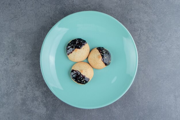 A blue plate of round cookies with chocolate 