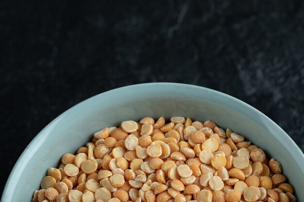 A blue plate with uncooked popcorn on black.