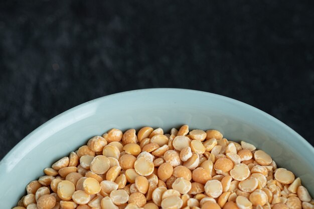 A blue plate with unprepared lentils in a dark