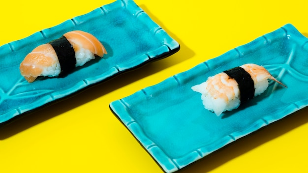 Blue plates with sushi on a yellow background