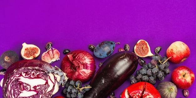 Blue, red and purple food. culinary background of fruits and vegetables. fresh figs, plums, onion, eggplant, grapes, cabbage, apple, garlic, dogwood, pomegranate, beetroot. violet background, flat lay