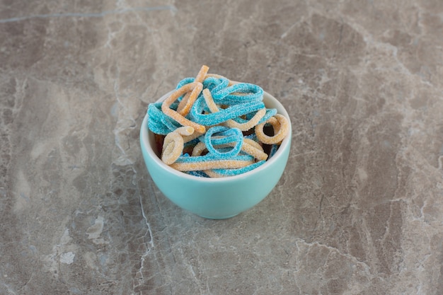 Blue ribbon candies. Colorful jelly candies in blue bowl over grey surface.