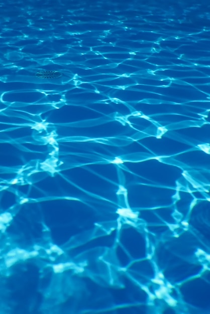 Free photo blue ripple water background, swimming pool water sun reflection 