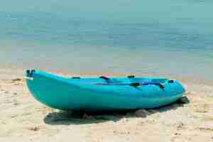 Foto gratuita barca a remi blu sulla spiaggia con il bellissimo mare sullo sfondo