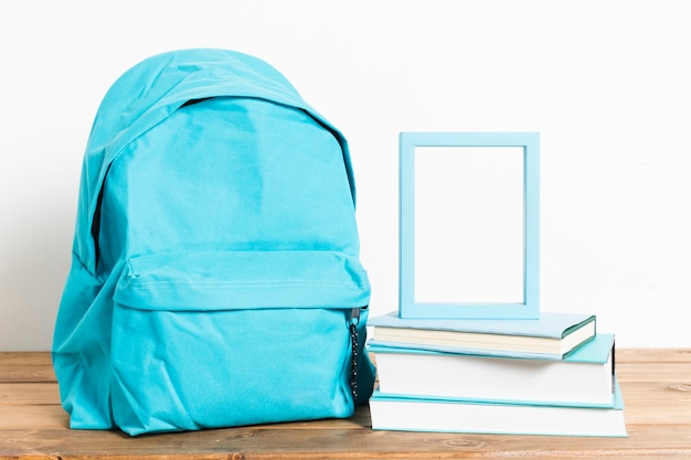 Синий школьный портфель с пустой рамкой на книгах на деревянный стол