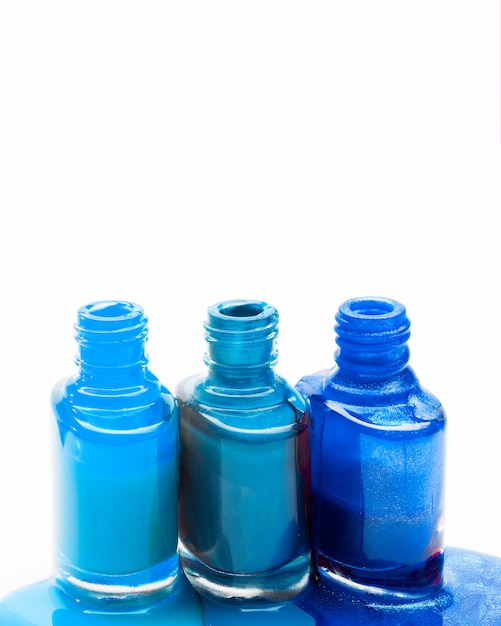 Blue shades of nail polish spilled around three opened bottles