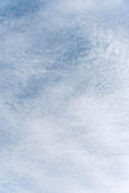 Голубое небо с ветреными облаками вертикальный снимок