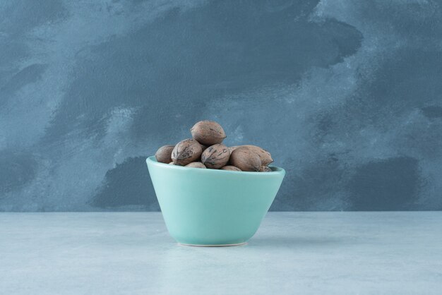 A blue small plate full of nuts on marble background. High quality photo