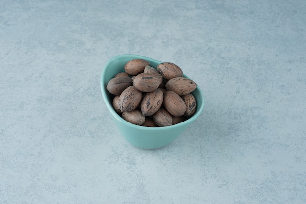 A blue small plate full of nuts on marble background. High quality photo