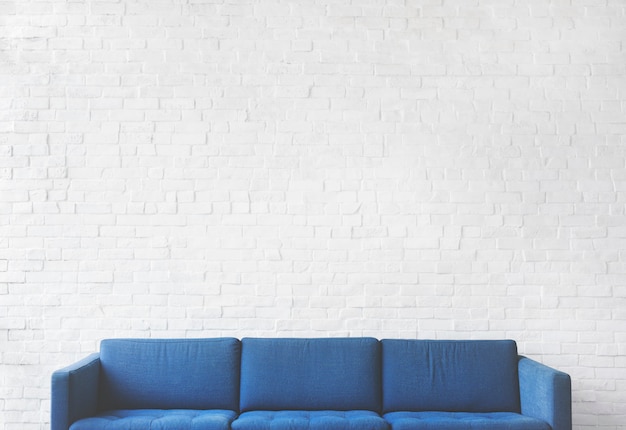Синий диван на фоне белой кирпичной стены