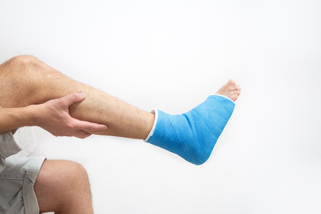 Blue splint ankle. Bandaged leg cast on male patient on white background isolated. Sports injury concept.