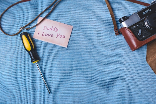 Blue surface with camera, screwdriver and note for father's day