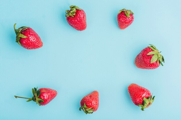 Blue surface with frame of strawberries